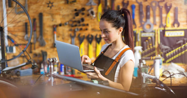 istock Woman using a laptop in a bicycle repair shop 945587954