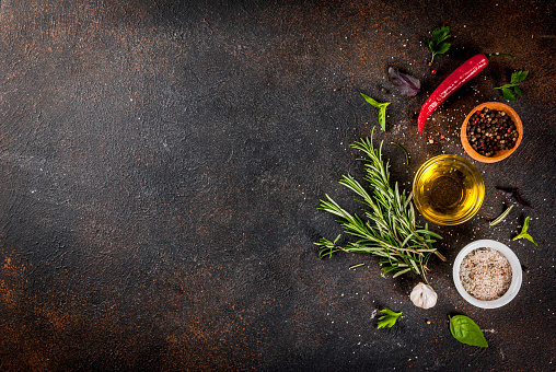Cooking background, herbs, salt, spices, olive oil, dark rusty background copy space top view