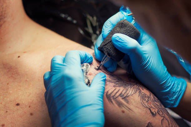 Female tattoo artist making tattoo on a men’s shoulder Tattoo process close-up. shoulder tattoo designs for men stock pictures, royalty-free photos & images