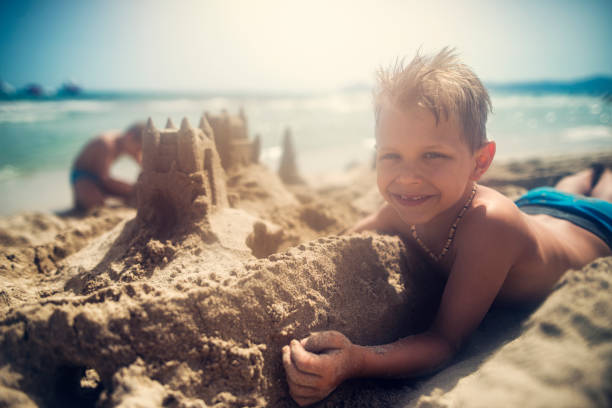 istock Kids building sandcastle on beach 945606338