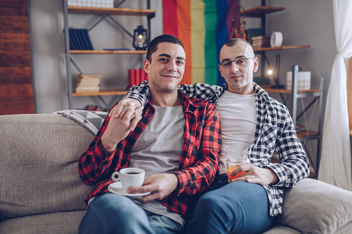 gay couple drinking coffee in the living room