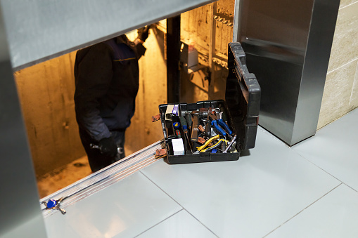 Specialist fixing or adjusting lift mechanism in elevator schaft. Regular repair, service and maintenance of elevator