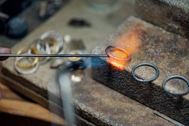 Professional Goldsmith at Work. Close up of a 3 silver rings being heated up, causing the tiny piece of silver in the middle to melt and join the ends together. Colour, horizontal  with some copy space. Photographed on location at her studio on the island of Møn in  Denmark. jewelry craftsperson craft jeweller stock pictures, royalty-free photos & images