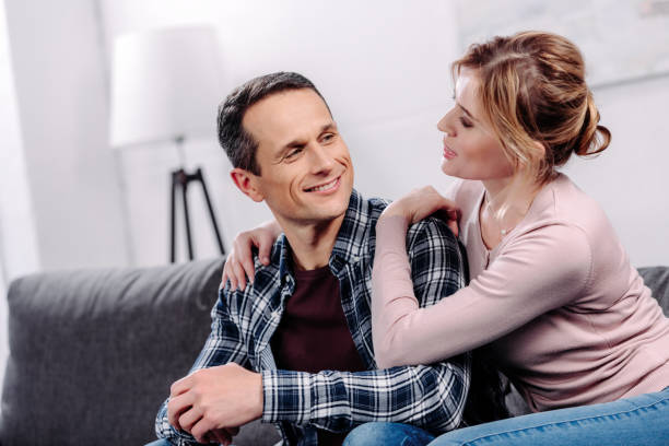istock portrait of smiling wife hugging husband while resting on sofa at home 945634562