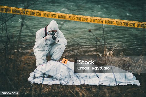 istock Photographer taking photos of crime scene by the river 945647254