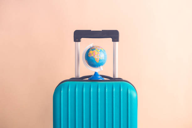 istock Luggage with small globe on beige background minimalistic vacation concept 945652606