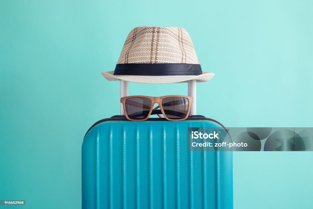 Luggage with woven beach hat and sunglasses on green background minimalistic vacation concept Suitcase with hat and sunglasses on pastel green background minimal creative travel concept Vacations Stock Photo