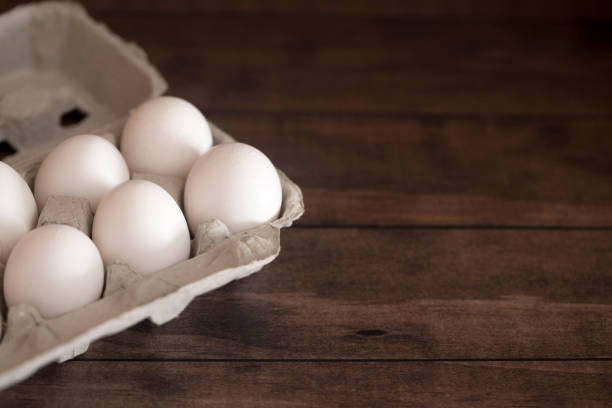 istock Farm Fresh White Chicken Eggs on a Dark Wood Table 945662236
