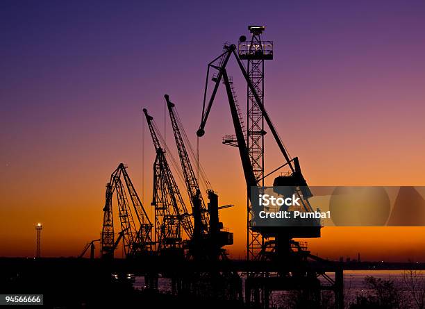 Silueta De Varios Cranes En Un Puerto Toma Durante La Puesta Del Sol Foto de stock y más banco de imágenes de Acero