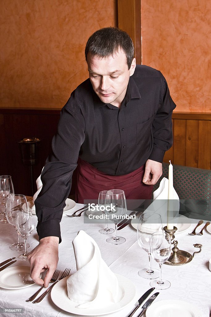 Macho camarero le ofrece platos en la mesa en el restaurante - Foto de stock de Ayuda libre de derechos
