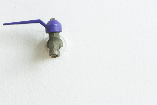 Close-up to faucet water on white wall background with copy space.
