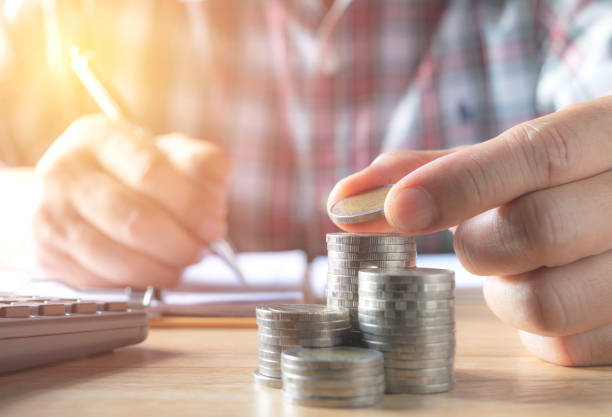 istock Men are Saint documents about save money  with  some coins calculator  on desk. 945703236