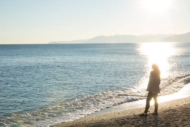 Woman pauses on beach at sunrise