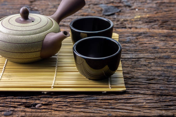 istock Hot tea pot on bamboo mat with cup on wooden table 945743492