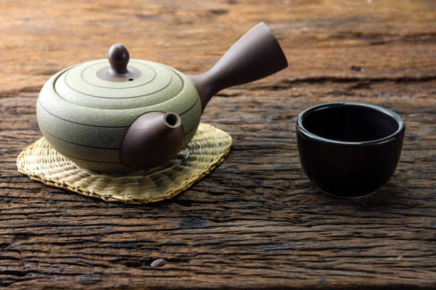 istock Hot tea pot on bamboo mat with cup on wooden table 945743520