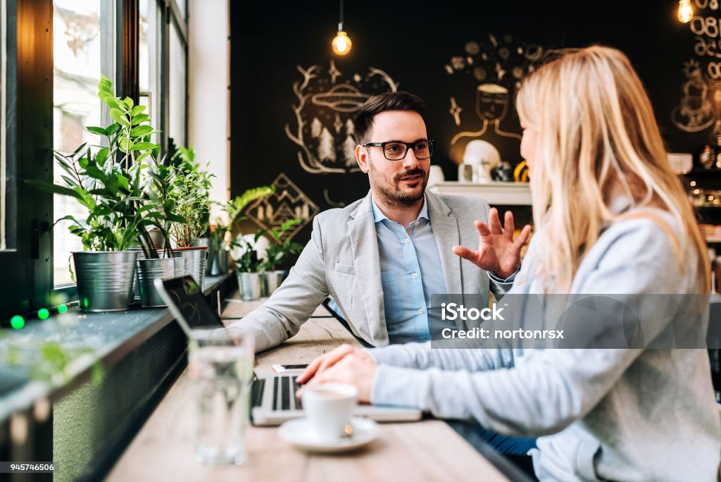 Handsome man talking to a young blonde woman at the cafe. Coffee - Drink Stock Photo