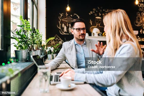 Handsome Man Talking To A Young Blonde Woman At The Cafe Stock Photo - Download Image Now