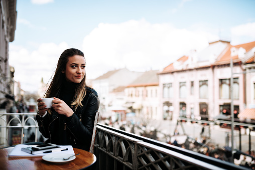 Woman drinking coffee on the balcony overlooking the city
