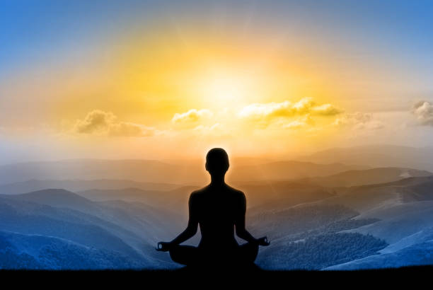 istock Yoga silhouette on the mountain in sunrays. The dawn sun 945768808