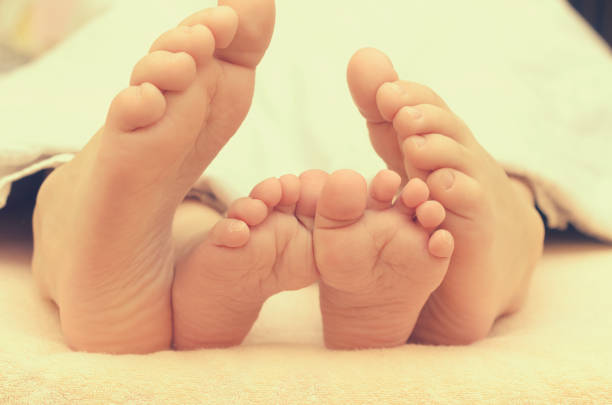 istock Baby feet from under the blanket on the bed. 945769860