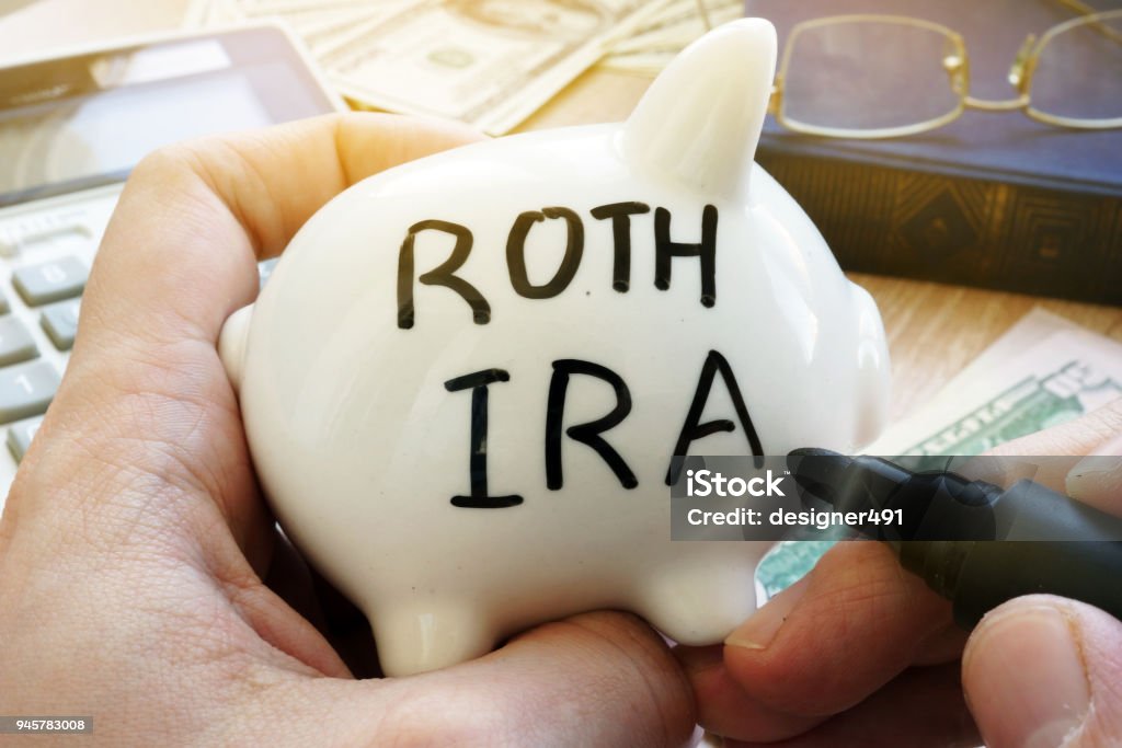 Hands holding piggy bank with Roth IRA. Pension plan. Pension Stock Photo