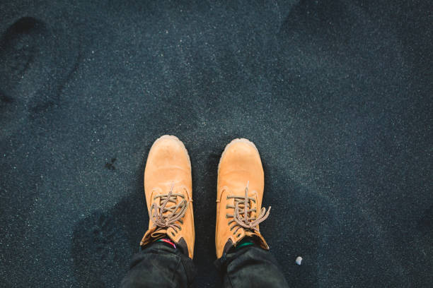 Man in hiking boots stand on black sand. Iceland. Top view. Copy space
