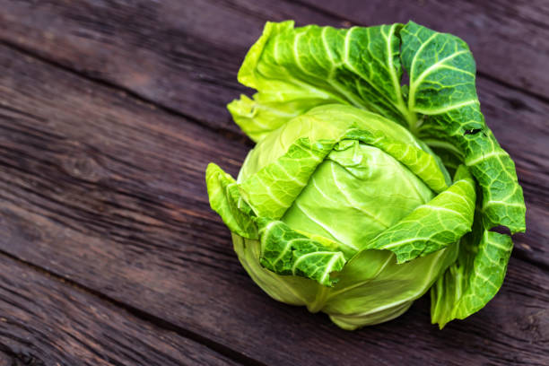istock Green fresh cabbage head on wooden surface 945786862