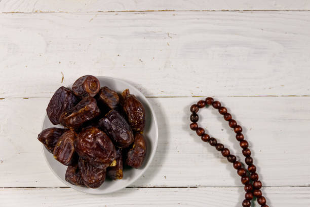 istock Dates fruit and prayer beads on white wooden table. Top view 945812534
