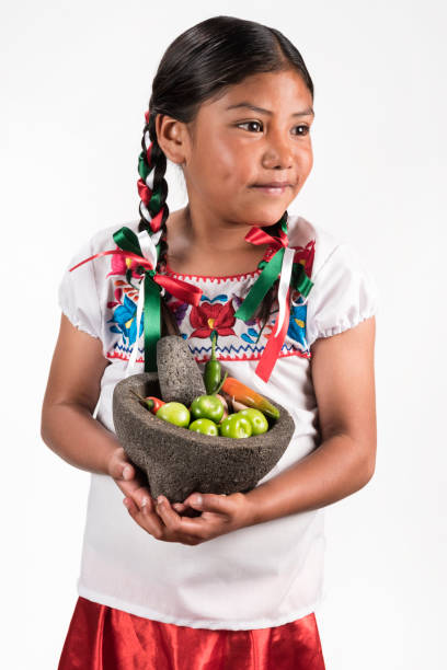 Portrait of a cute Latin little girl over white backgroundShot of cute girl with a mortar and ingredients for salsa