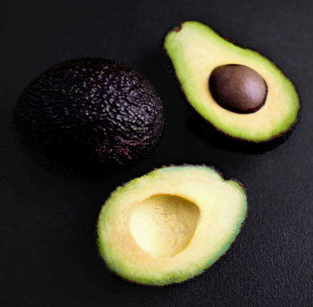 istock Avocado on a black background. Half of avocado close up. Top view. Copy space