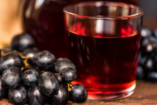 istock Red grape juice in glass and grapes close 945853350