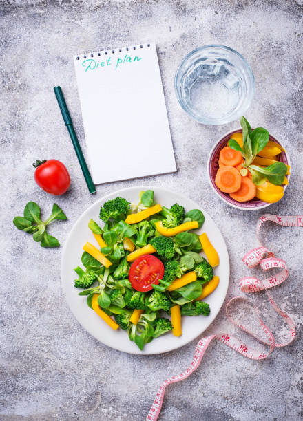 istock Healthy vegetable salad, water and measuring tape 945857722