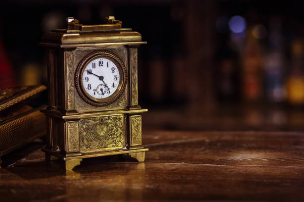 reloj antiguo de pie sobre una mesa de madera - reloj antiguo fotografías e imágenes de stock