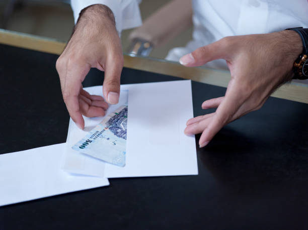 istock Businessman hands taking money out of an envelope 945866464
