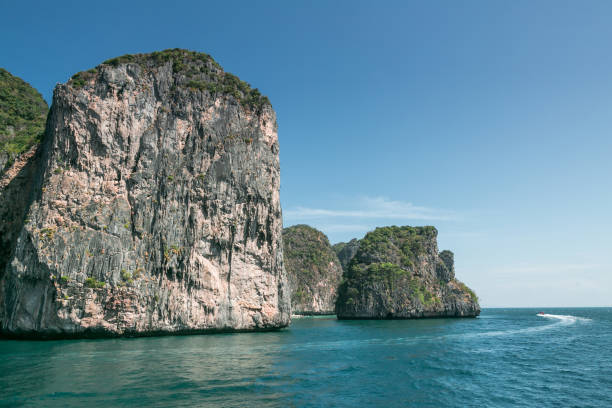 istock scenic view of rocky formations covered with green plants, blue sky and ocean in phi phi islands 945873564