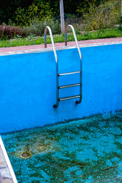 istock Empty abandoned swimming pool with metal ladder 945881310