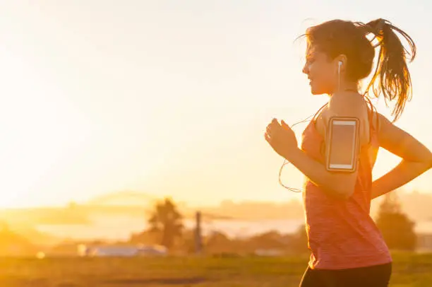 Photo of Woman running with mobile phone on her arm.