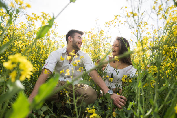 istock Beautiful young couple between grass and flowers laughing 945889000