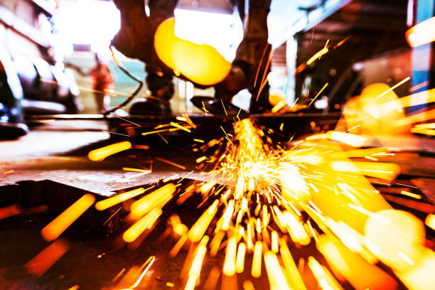 Metal grinder sending sparks all over the camera as he grinds down a metal plate's edge.