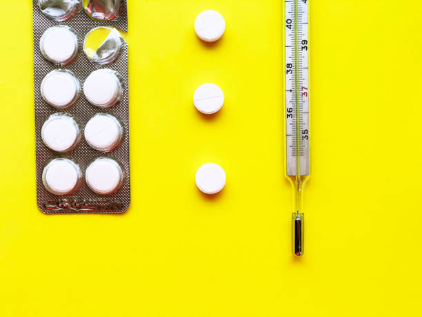 istock Pills, thermometer on a yellow background, top view. 945898348