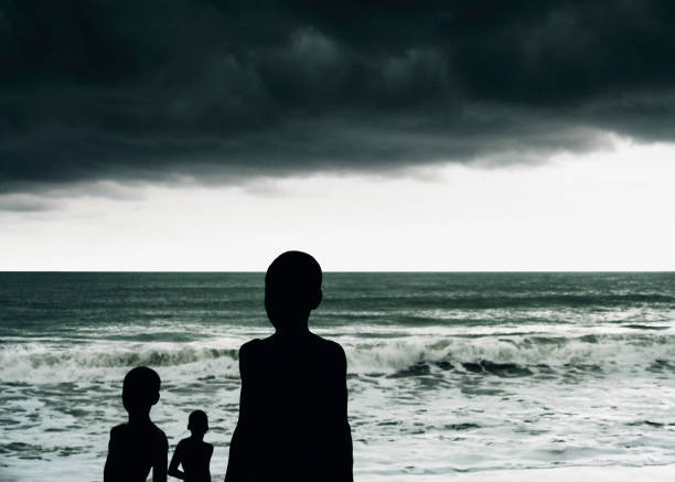 olhando para os céus tempestuosos - benin, áfrica ocidental - silhouette three people beach horizon - fotografias e filmes do acervo