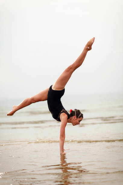 bella giovane ginnasta femminile che fa spaccate sulla spiaggia - ballet dancer ballet dancer the splits foto e immagini stock