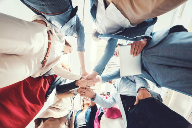 istock Group of business people cheering and holding hands 945909026