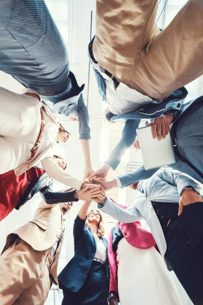 istock Group of business people cheering and holding hands 945909090