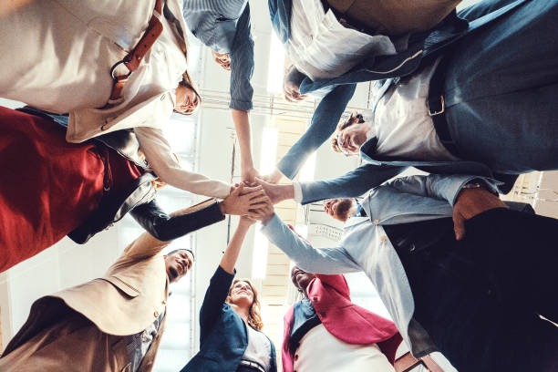 istock Group of business people cheering and holding hands 945909146