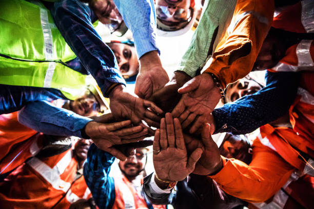 Steel Industry Workers putting their hands together while in a circle. Unity among the blue collar employees and the owner india crowd stock pictures, royalty-free photos & images