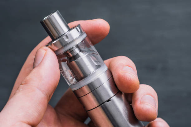 istock young man vape electronic cigarette cloud by using a mod, smoke tricks of vaping device background. 945928352