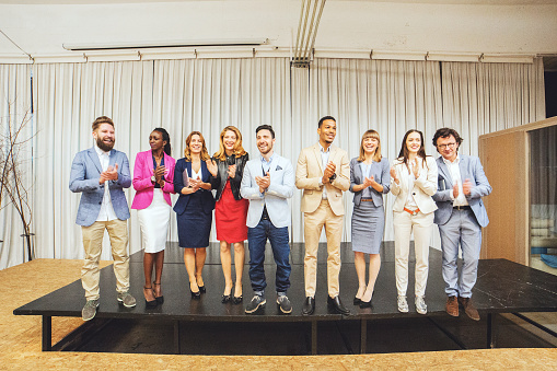 Group of successful business people clapping in the office.