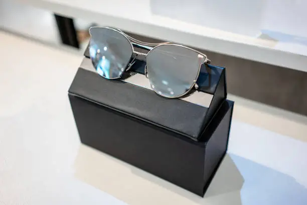 Photo of Sun glasses with packaging box in the shop display shelves. Selective focus