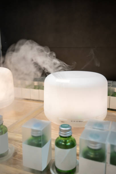 istock Electric aroma oil diffuser on wooden floor against black background 945938886